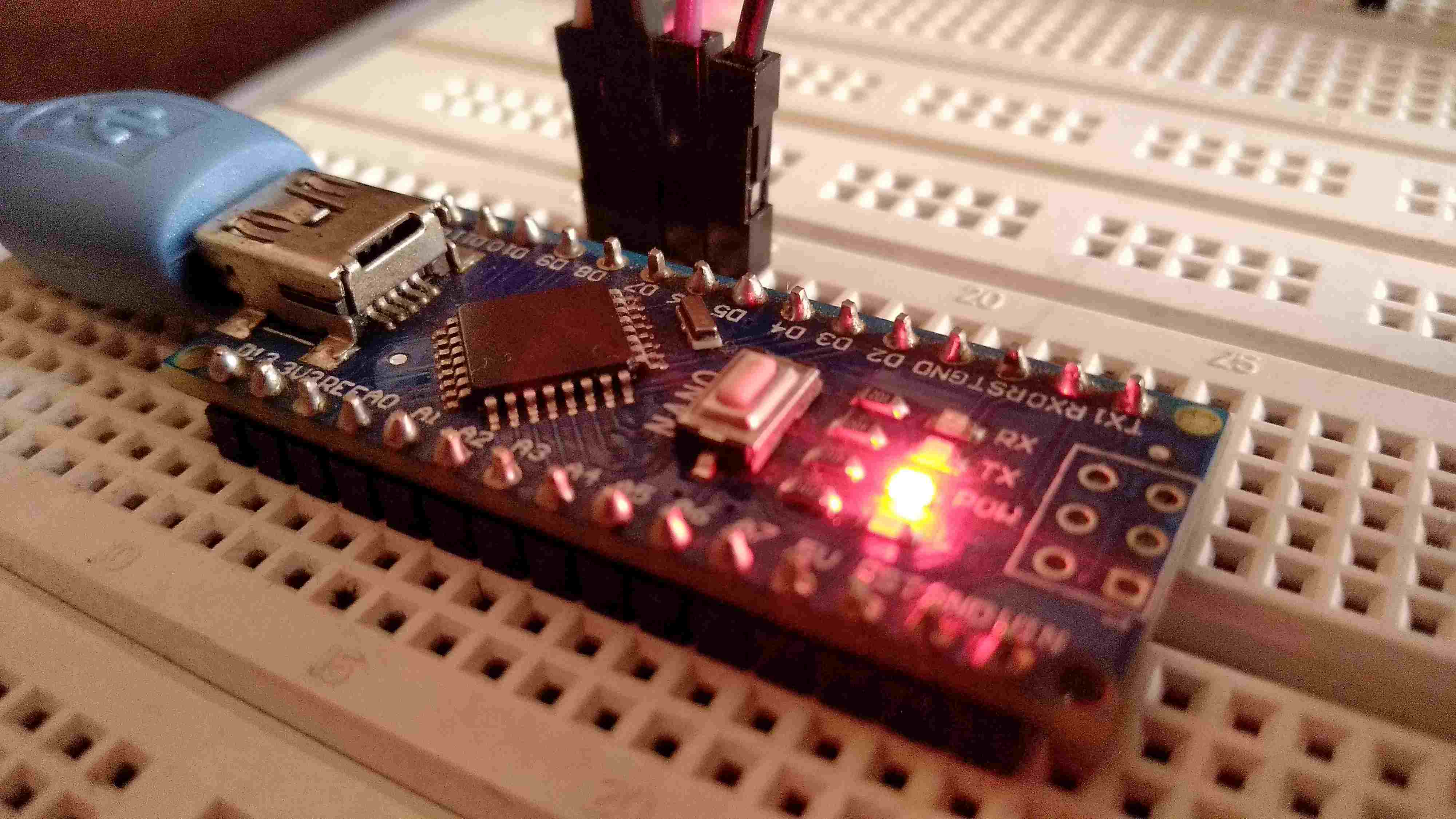 AVR microcontroller development board with USB programmer on breadboard, illuminated LEDs indicating power and serial commun…